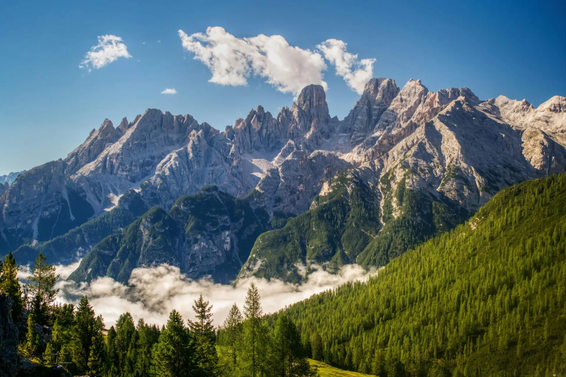 Breathtaking view of the Dolomites mountains under a clear blue sky, showcasing lush green valleys.