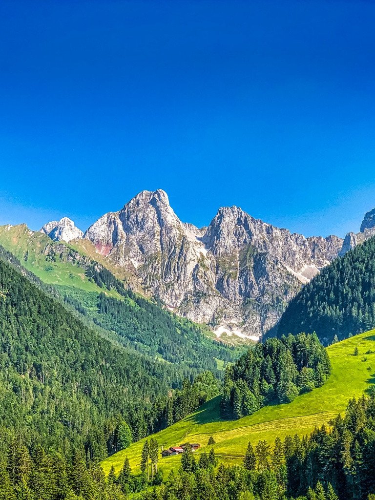 Alpine mountain range with green valley under clear sky