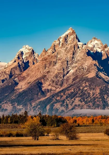 Breathtaking autumn landscape of Grand Teton with snow-capped peaks and colorful trees.